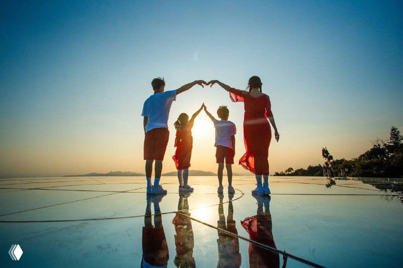 Силуэт семьи из четырёх человек на пляже Саньи на закате, отражение на влажной поверхности и тёплый небесный градиент над морем.