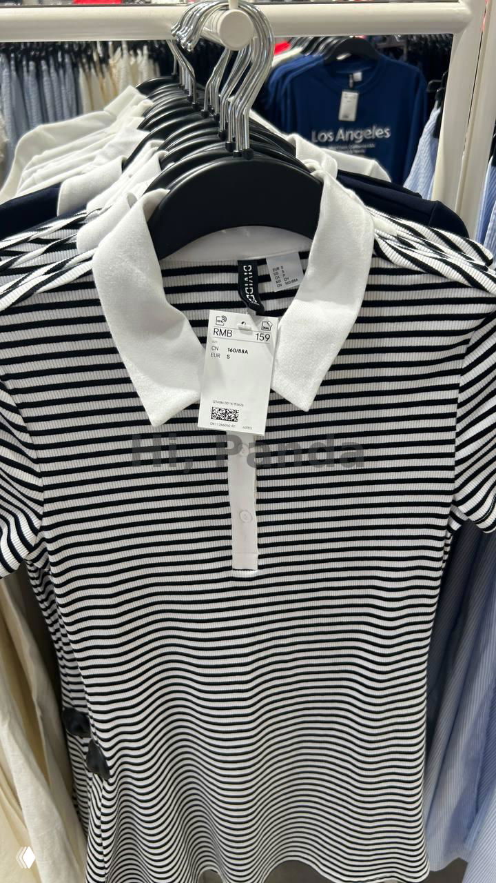 Полосатая футболка-поло на вешалке в магазине H&M внутри ТЦ Mangrove Tree Sanya; видно ценник в юанях и бирку бренда, крупный план товара на полке.