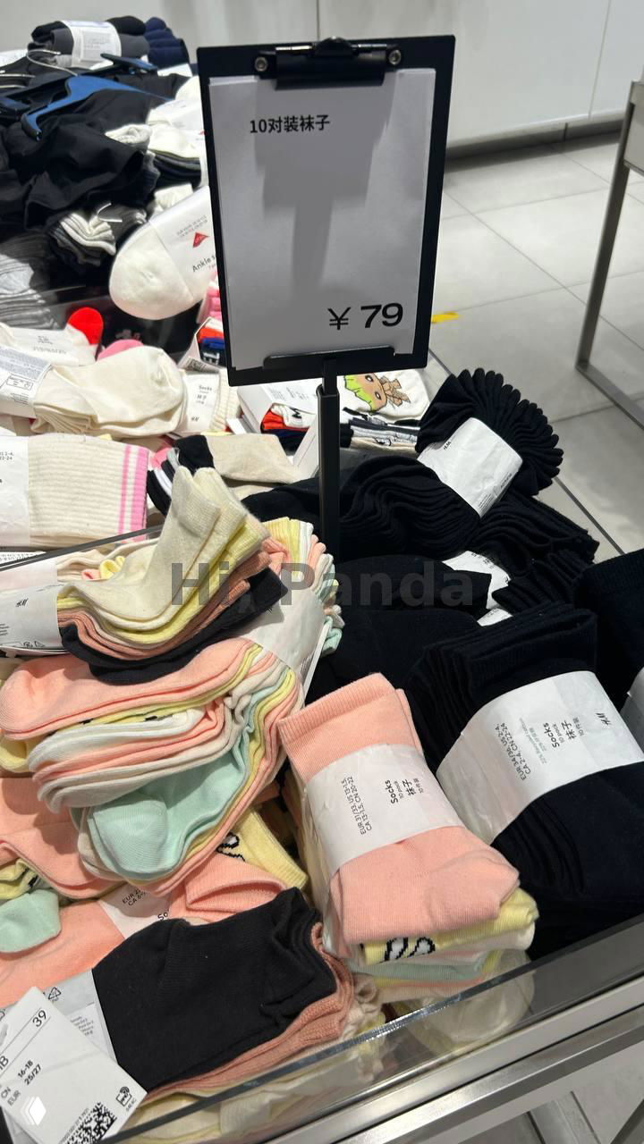 Стойка с носками и упаковками по цене ¥79 в магазине внутри ТЦ, крупный план ценника и разноцветных носков, торговая выкладка и ценовая маркировка на китайском.