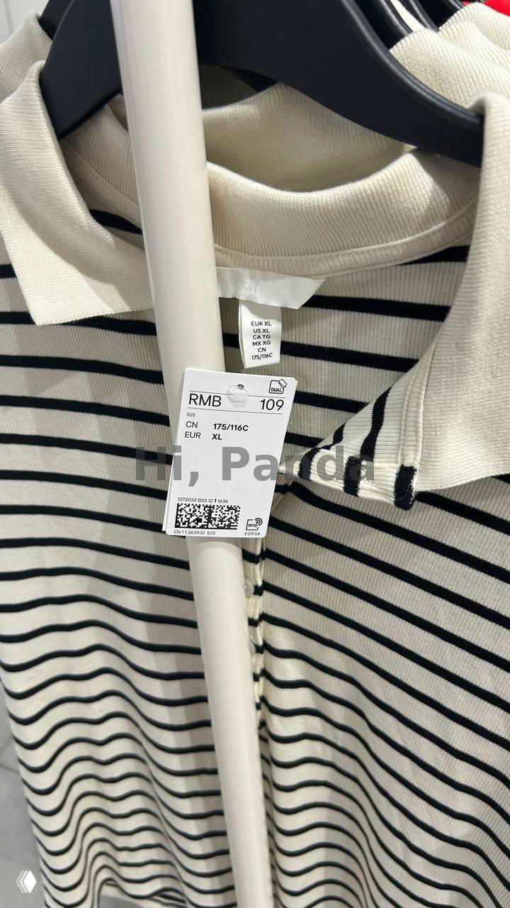 Ещё один крупный план полосатой футболки и её ценника RMB 109 на вешалке; видна текстура ткани, бирки и структурa торговой стойки в магазине H&M.