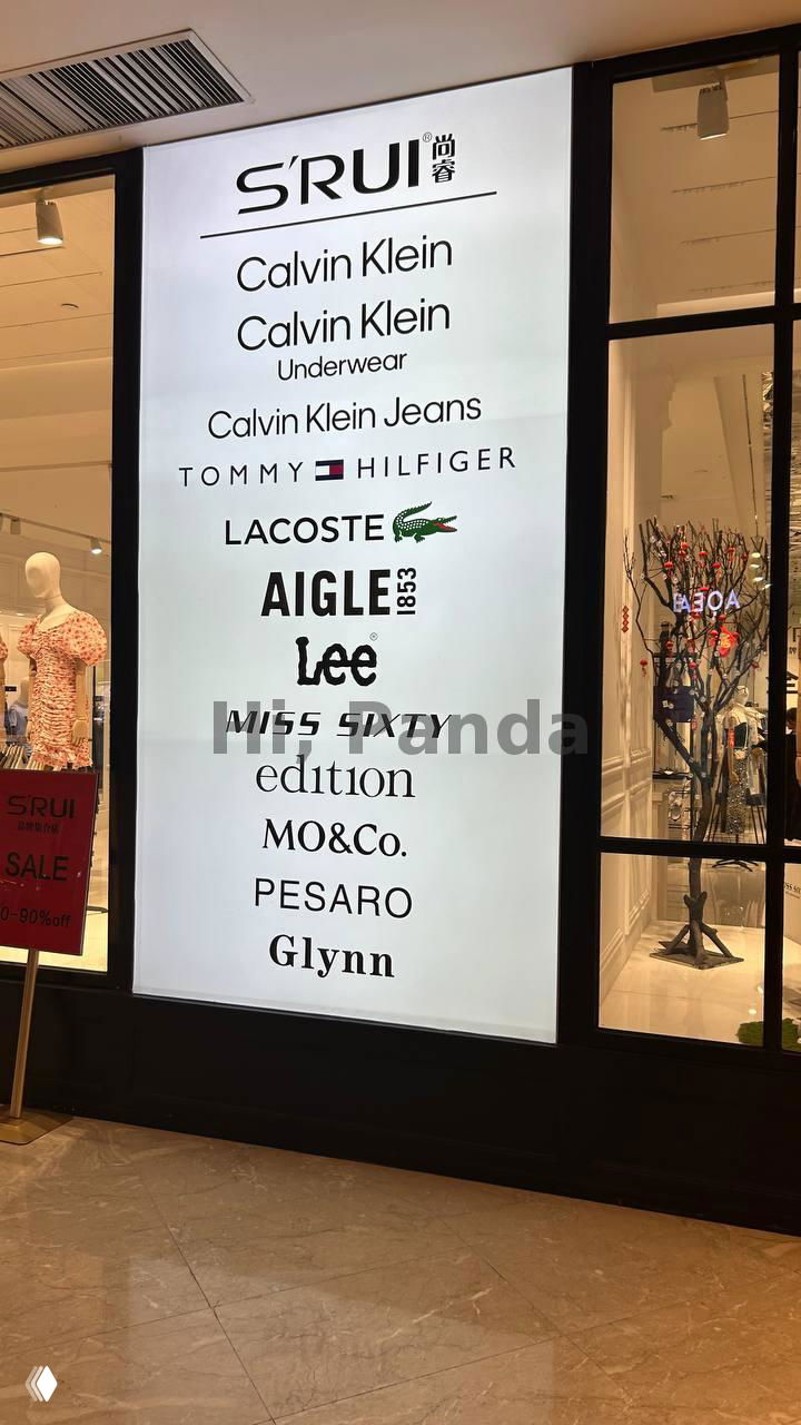 Большая световая панель со списком брендов: Calvin Klein, Tommy Hilfiger, Lacoste и другие — афиша брендов внутри торгового центра.