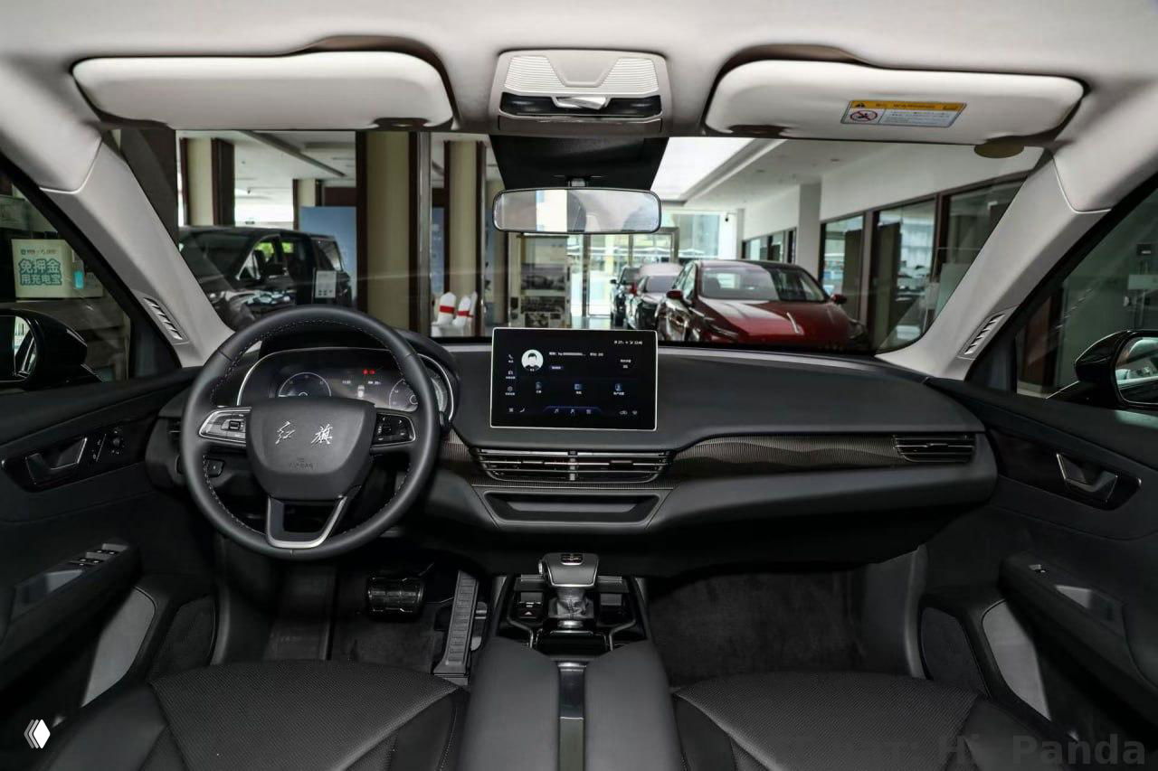Интерьер премиум‑автомобиля на Хайнане: вид на рулевое колесо, цифровую приборную панель и крупный центральный сенсорный дисплей с качественной отделкой салона.