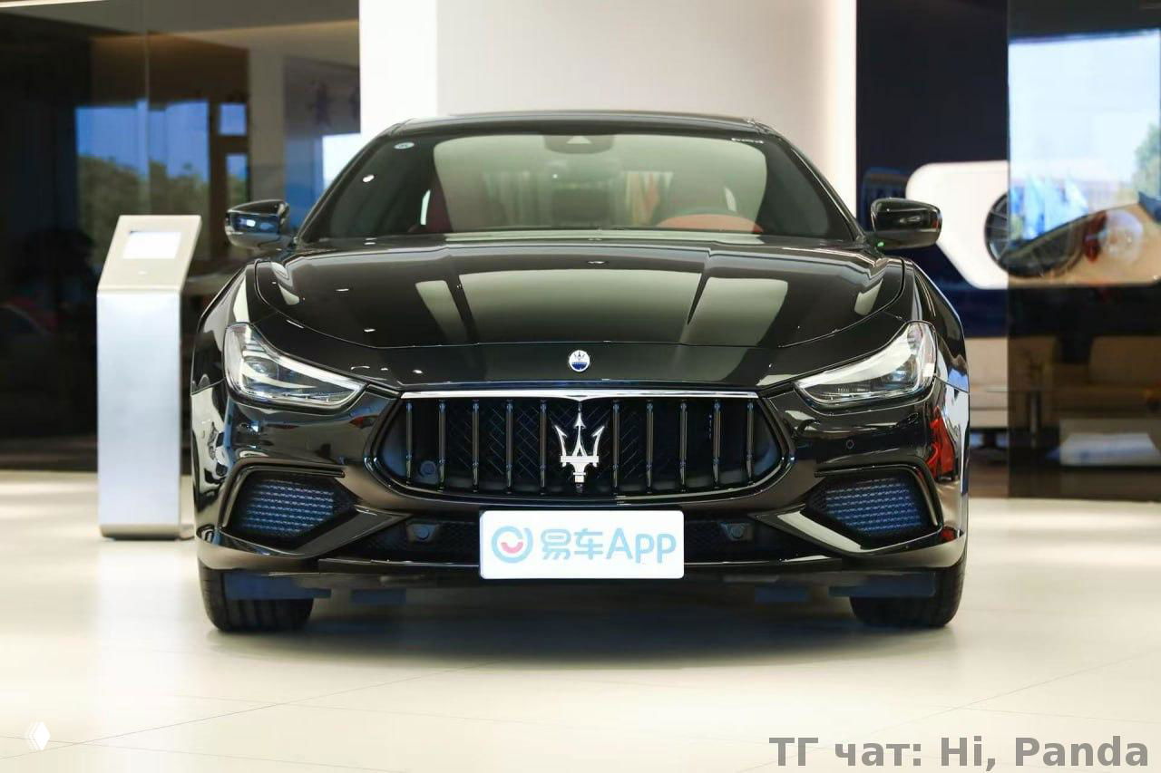Фронтальный вид Maserati в шоуруме: характерная решётка радиатора с тризубцем, лаковое чёрное покрытие кузова и выразительная форма капота автомобиля.