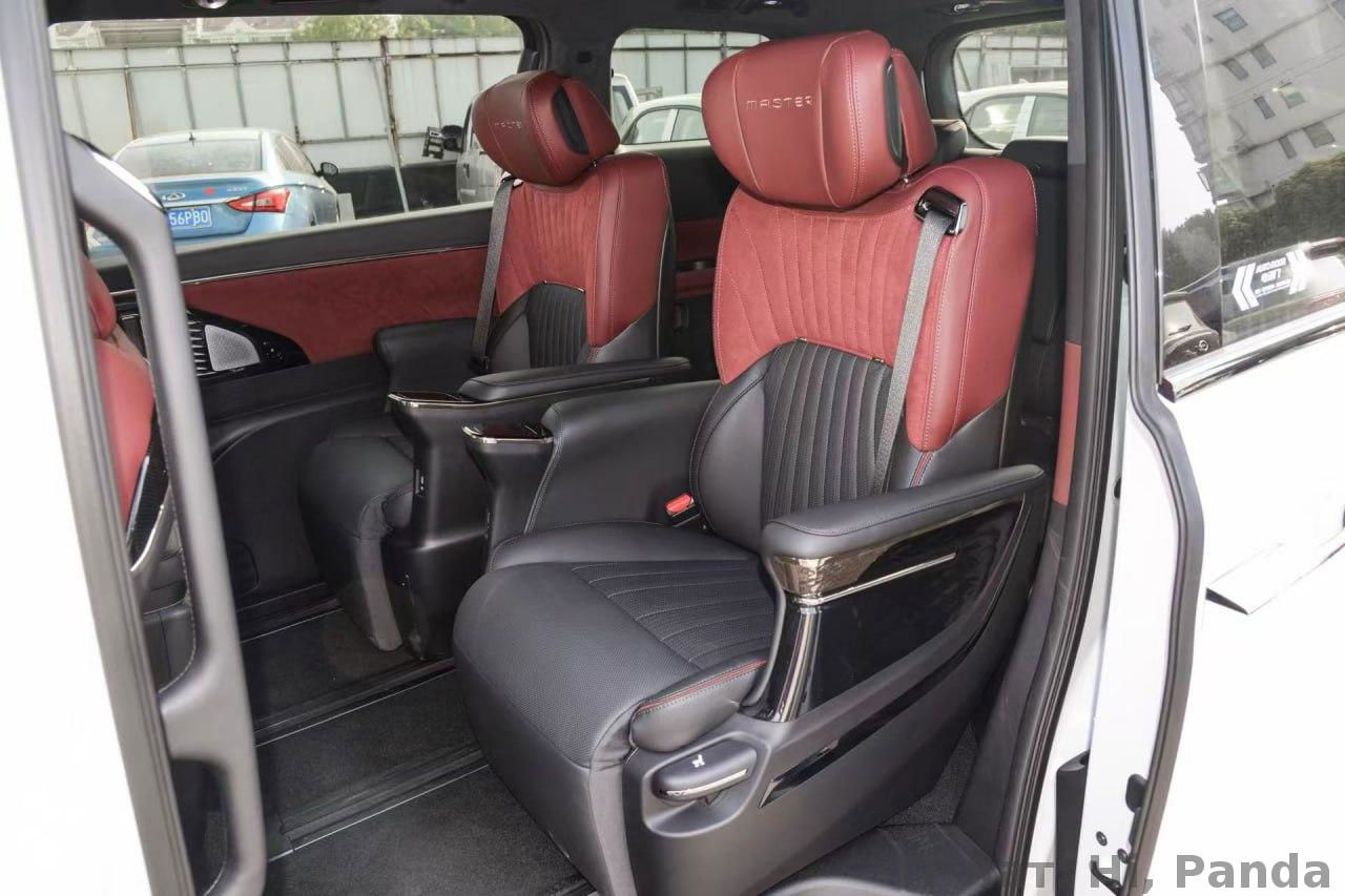 Внутренний вид салона минивэна: два капитанских кресла в красно‑чёрной коже, подлокотники и элементы комфортабельной отделки, крупный план для детального обзора.