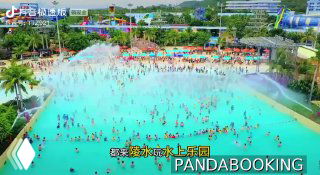 Панорамный вид аквапарка рядом с парком Fuli: крупный бассейн с множеством отдыхающих, разноцветные горки, зонты, пальмы и дорожки для прогулок.