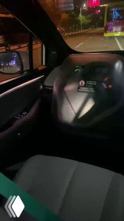 Кадр с торпедо и рулевой колонкой беспилотного автомобиля, где видно отсутствие традиционного водителя и экран центральной консоли с интерфейсом управления.