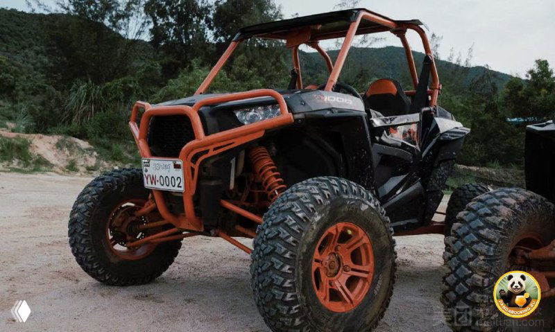 Оранжевый внедорожный багги на грунтовой дорожке Хайнаня, вид на колёса и раму, на фоне тропической зелени и холмов.