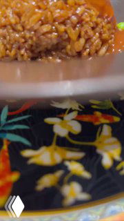 Крупный план блюда с рисом в соусе на украшенной цветочным орнаментом тарелке, кадр подачи морепродуктов на Хайнане.