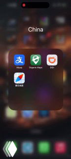 Скриншот экрана смартфона: папка «China» с иконками AliPay, DiDi и другими приложениями на фоне рабочего стола телефона, крупный план.