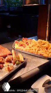 Тарелка с кусками жареного мяса рядом с большим подносом картофеля фри на станции шведского стола BBQ в отеле Pullman Oceanview Sanya Bay Resort, вечерняя сервировка.