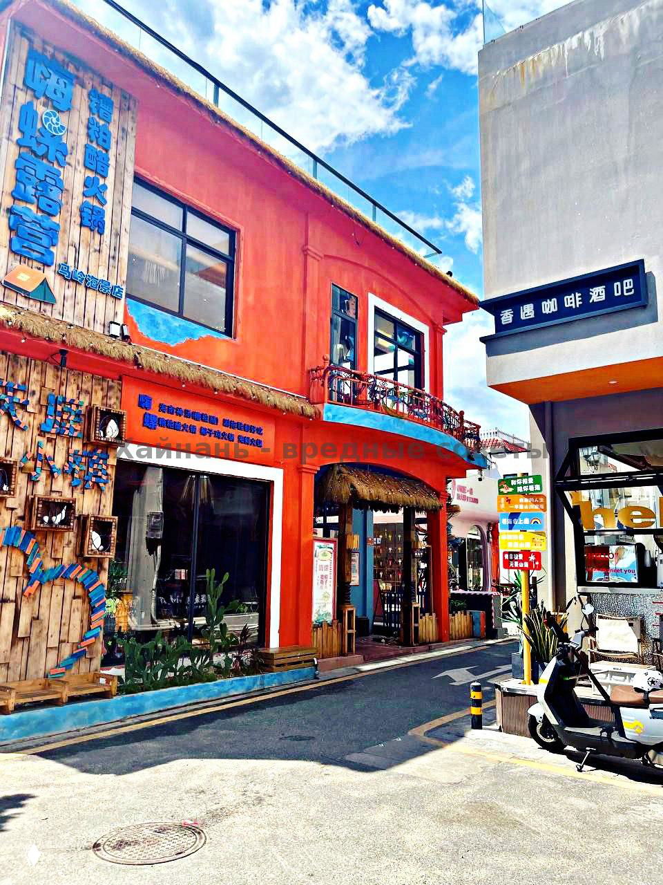 Улица туристического городка Танья с ярким оранжевым двухэтажным зданием, деревянными декорациями и синем небом над крышей в солнечный день.