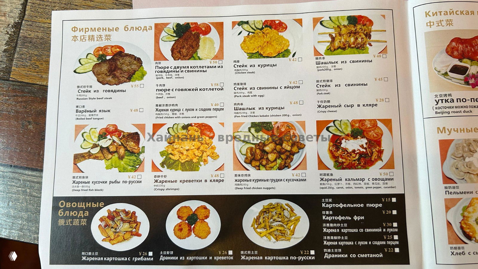 Большая фотография меню с фирменными блюдами и русскими подписями, отображены стейки, курица, жареная рыба и овощные блюда с ценами в юанях.