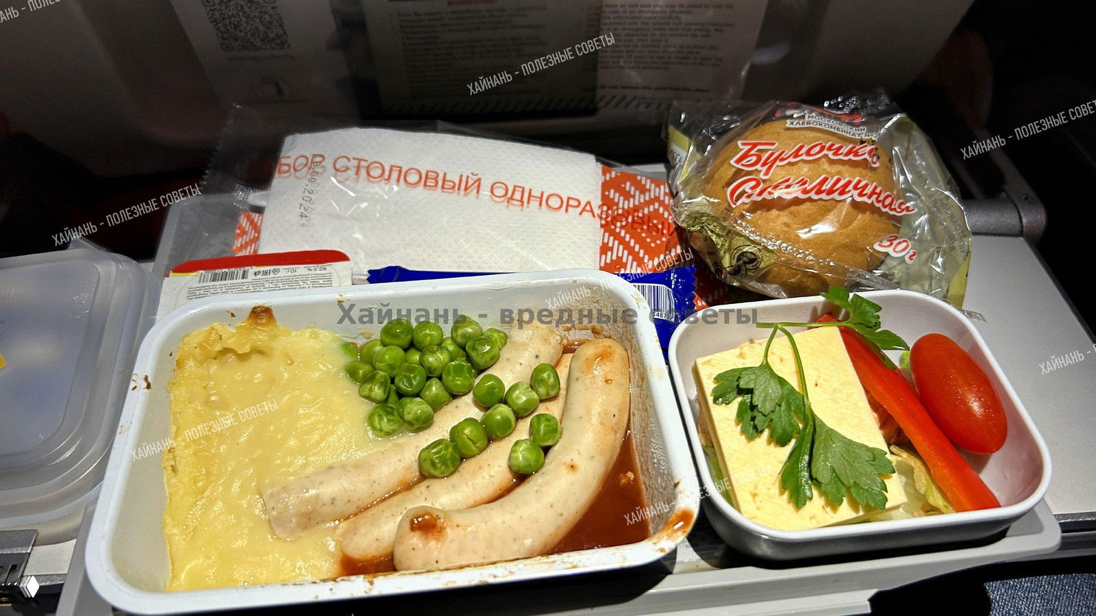 Ближний план второго варианта бортового обеда: колбаски, горох, картофельное пюре и овощная закуска на подносе.