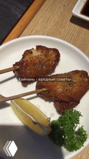 Близкий план жареных закусок на тарелке: две шпажки с обжаренным мясом, кусочек лимона и петрушка рядом, сервировка в кафе.