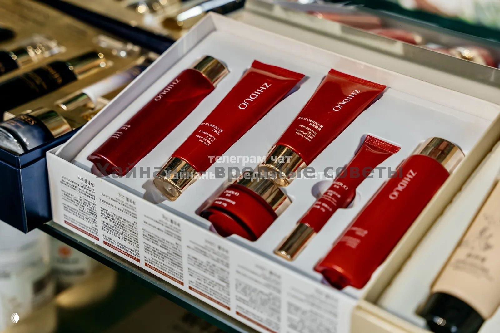 Набор косметики и уходовых средств в красной упаковке, аккуратно уложенные в коробке на витрине магазина «Hi, Panda».