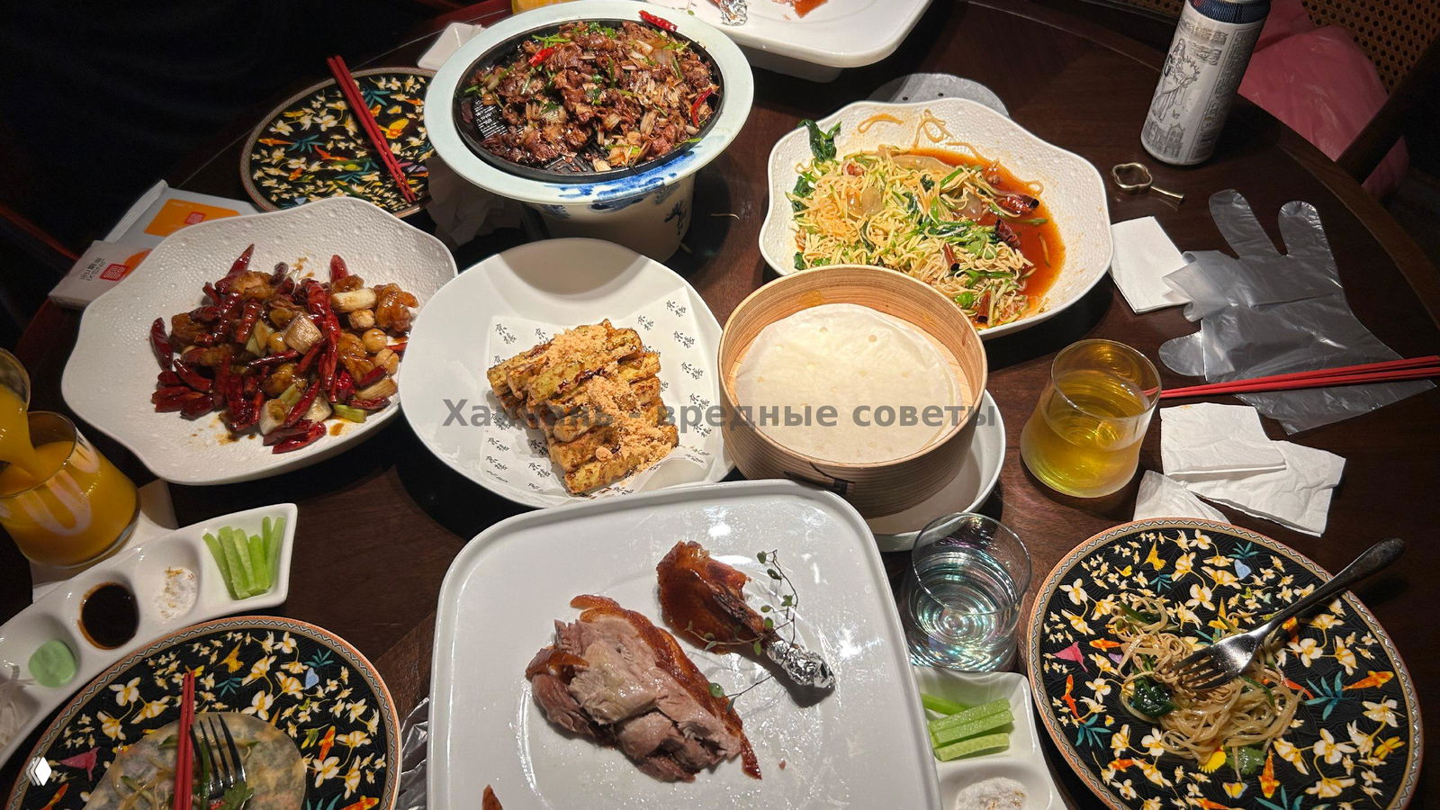 Стол с поданными китайскими блюдами: тарелки, блинчики для утки, порции и сервировка рядом с кусочком поданной утки.