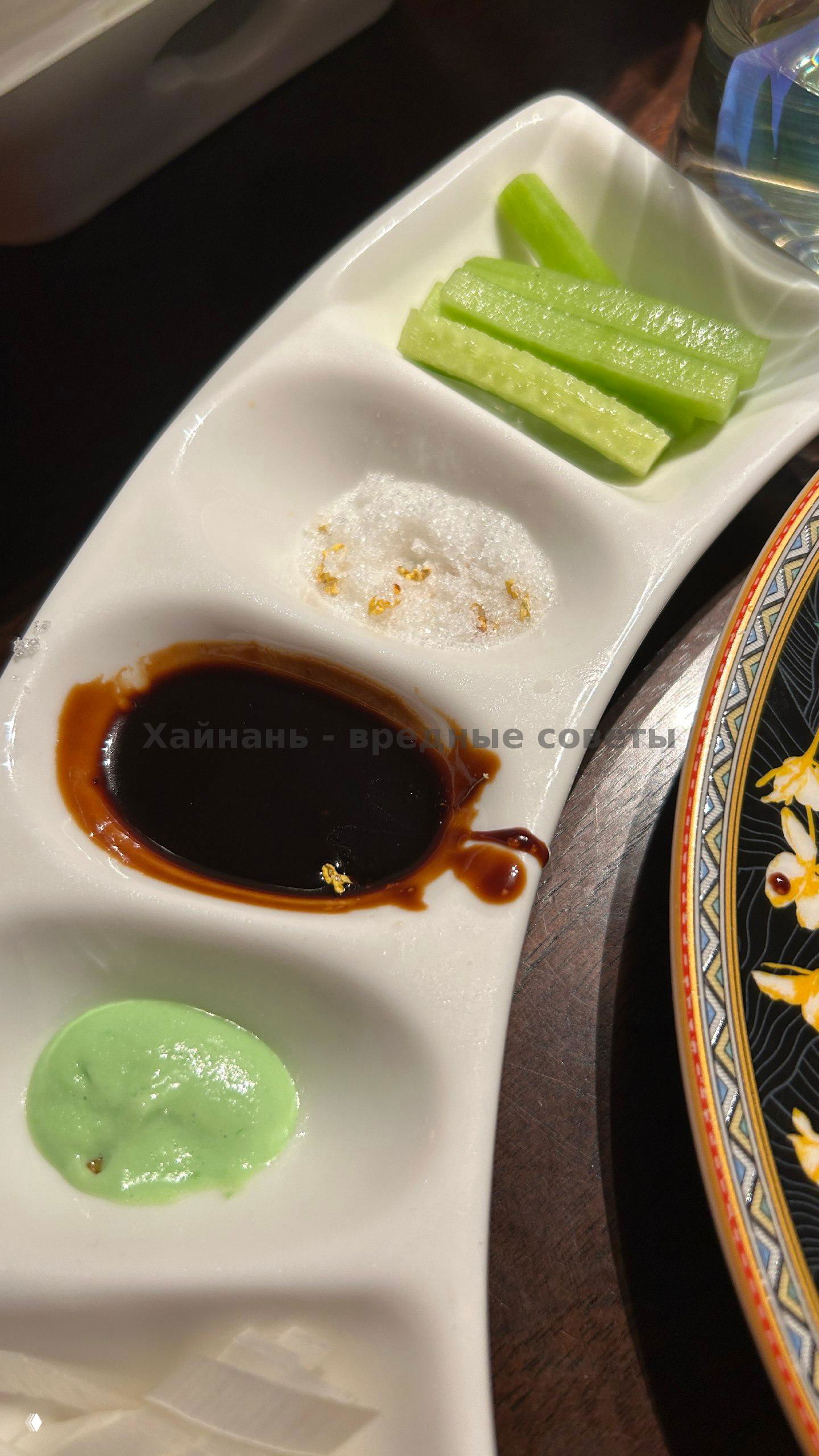 Набор соусов и палочки: тёмный соус, васаби и соль рядом с ломтиками огурца — сервировка к утке по‑пекински.