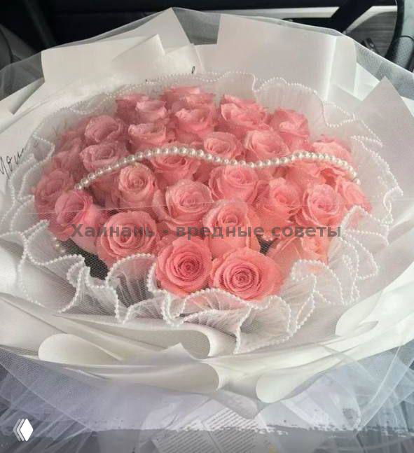 Роскошный букет ярко-розовых роз, упакованных слоями белой бумаги и украшенных жемчужной нитью, элегантный вариант для романтической доставки в отель.