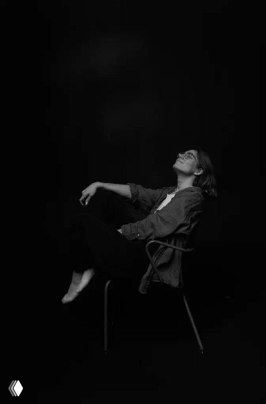 Чёрно‑белый портрет: женщина (автор канала) сидит на стуле, откинувшись назад и смотрит вверх, атмосферный минималистичный кадр.