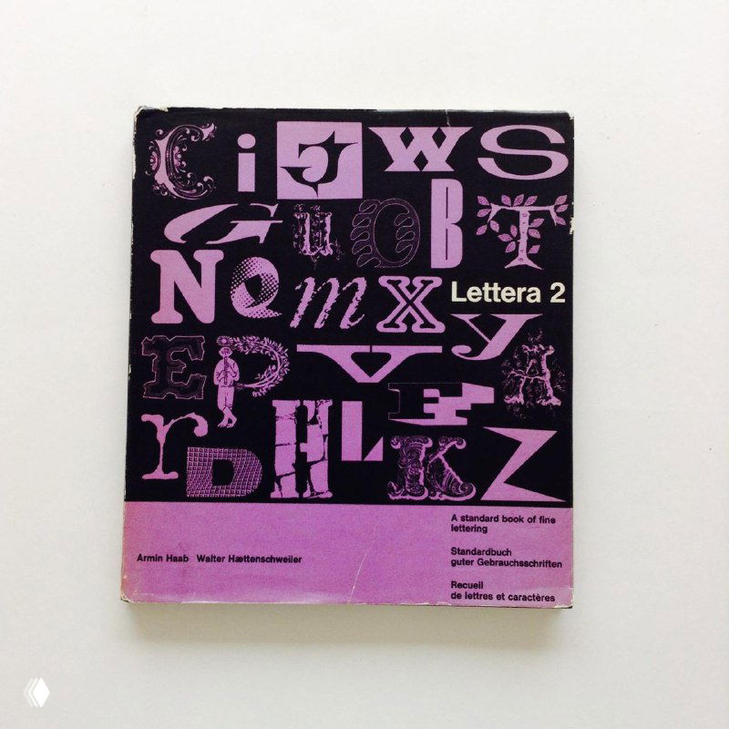 Изображение обложки фиолетового издания с набором декоративных букв и заголовком «Lettera 2», снято на светлом нейтральном фоне.