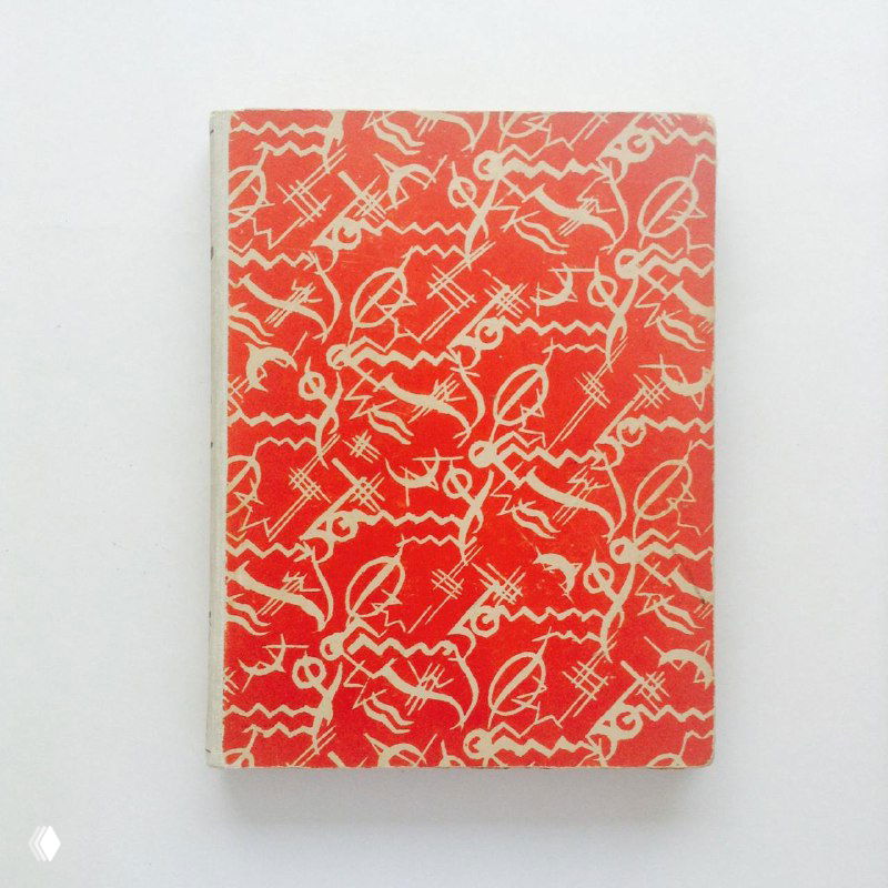 Фотография красно-белой обложки старой книги с повторяющимся орнаментом, видна фактура бумаги и лёгкий износ краёв.