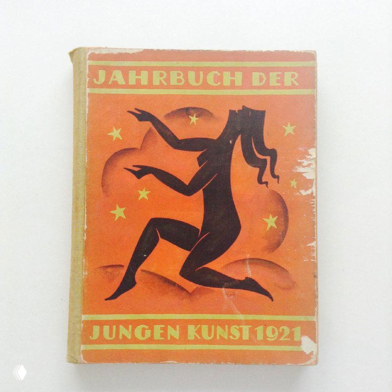Фотография оранжевой обложки с силуэтом человека и надписью на немецком языке, видна винтажная потертость и дизайн 1920-х годов.