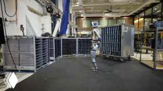 Кадр из видео: человекоподобный робот Atlas от Boston Dynamics на складе перемещает ящик и адаптирует походку к окружению