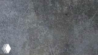 Превью ролика: текстурированная серая поверхность (бетон/камень) с небольшим белым логотипом внизу слева, нейтральный фон, кадр из клипа.