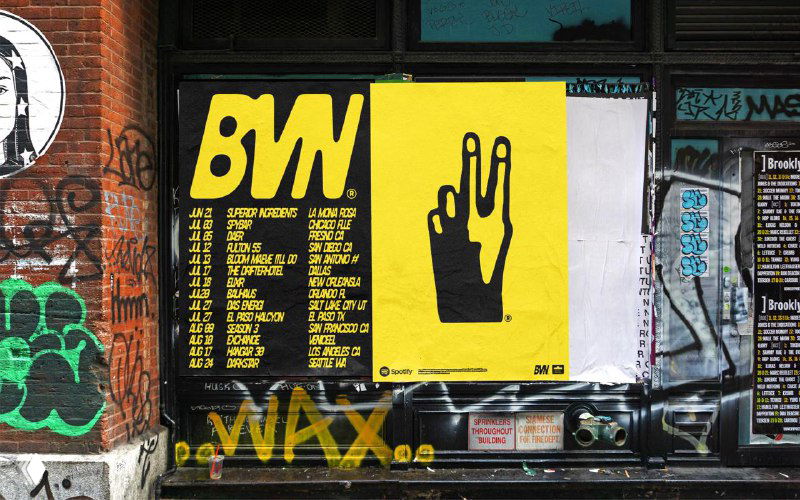 Уличный постер с жёлтым фоном и чёрным логотипом BVN — промо‑афиша с типографикой и графическим знаком, демонстрирующая уличное применение бренда.