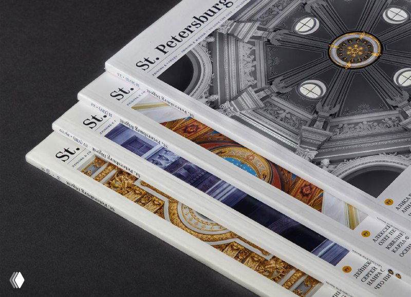 Стопка выпусков журнала St. Petersburg Digest — видны корешки и обложки с орнаментами и архитектурной фотографией на тёмном студийном фоне.