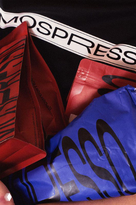 Набор разноцветных пакетов Mospresso — красные и синие упаковки с крупной типографией; кадр демонстрирует повторяемый брендовый паттерн и фактуру материалов.