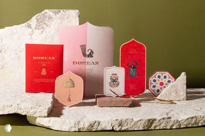 Коллекция брендированных материалов Dorean — меню, бирки и орнаменты в красно-розово‑зеленой палитре с золотым тиснением, выполненные для презентации ресторана.