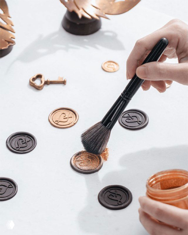 Процесс нанесения металлических печатей и декоративных элементов для упаковки LaFuong; видны кисточка, металлические медальоны и текстуры материалов.