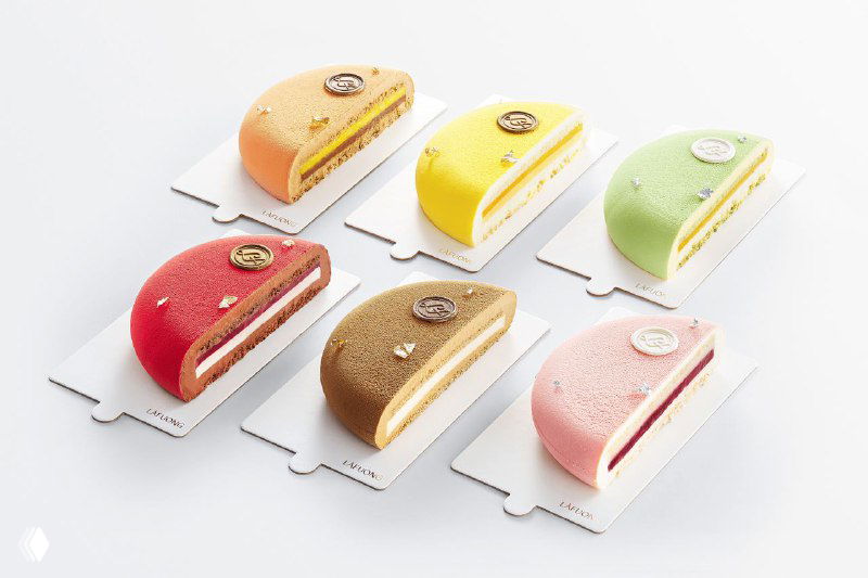 Ряд порционных тортов разных ярких вкусов и цветов, каждый на подложке — эстетическая фуд-фотография, подчёркивающая форму и текстуру десертов.