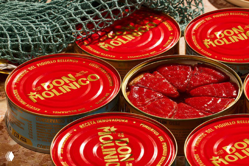 Крупный план раскрытой банки Don Molinico: томатная масса внутри, вокруг — яркие красные крышки и ретро-этикетка с золотыми акцентами и текстурой.