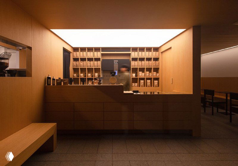 Интерьер кофейни в тёплой деревянной отделке: стойка, полки и минималистичный дизайн пространства, соответствующий фирменному стилю.