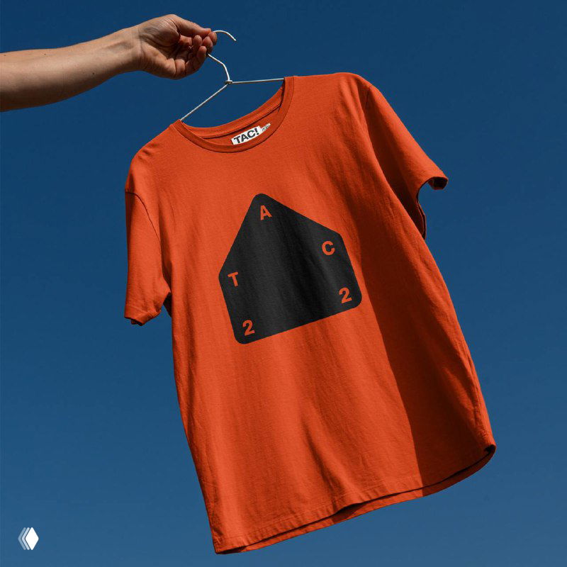 Оранжевая футболка с логотипом TAC: висящая на вешалке демонстрация айдентики на контрастном фоне неба