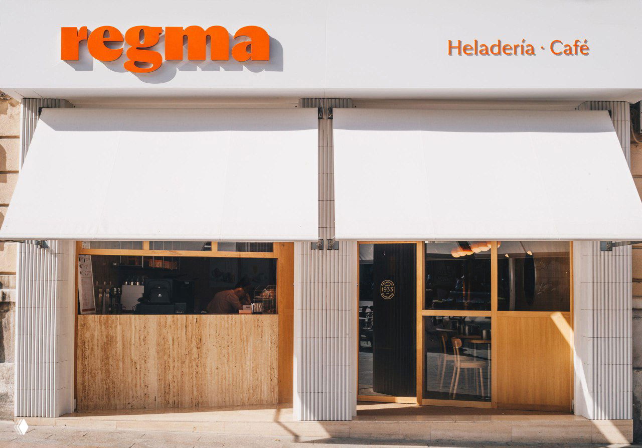 Фасад магазина Regma с объёмным оранжевым шильдом и аккуратным оформлением витрины, пример применения айдентики в реальном пространстве.
