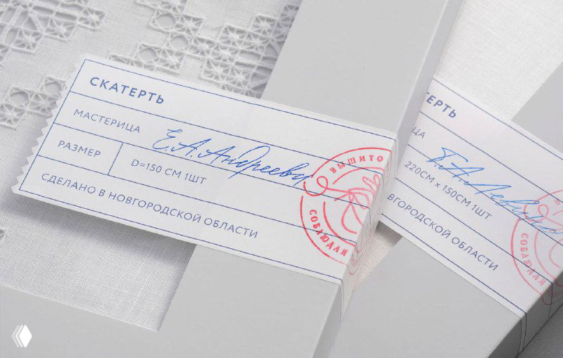 Деталь упаковочной этикетки и штампа фабрики на стикере и коробке, где видны рукописные записи мастерицы и пометки о регионе изготовления.