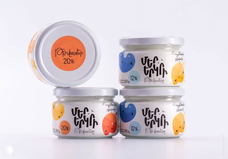 Вид сверху на металлические крышки баночек Mer Yerkir с яркими кругами цвета и указанием процентного содержания жира.