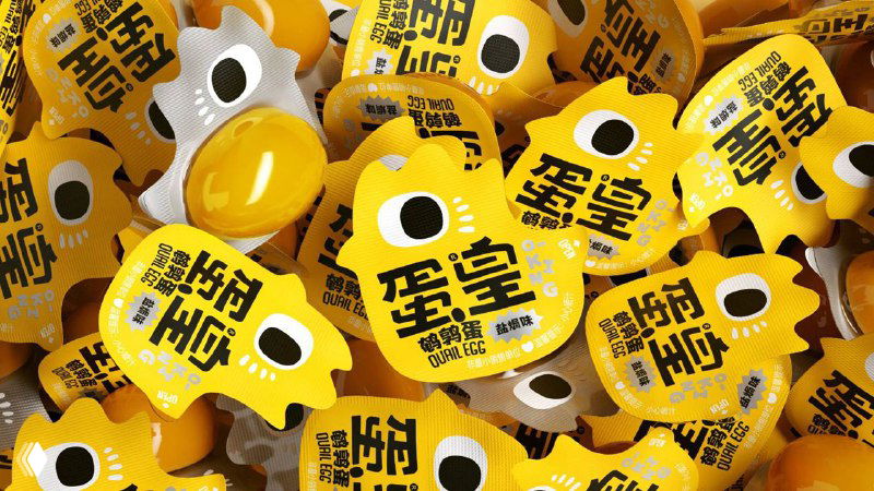 Крупный план яркой желтой упаковки перепелиных желтков с графическим «глазком» и контрастным логотипом — видимый дизайн в жёлтой палитре.