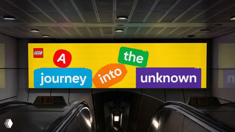 Рекламный щит в пространстве города с цветной фразой и набором разноцветных плиток, иллюстрирующий наружную рекламу новой айдентики LEGO.