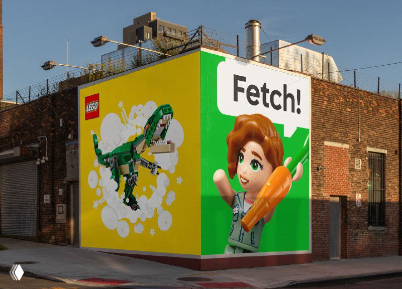 Уличный мурал на кирпичной стене с крупным изображением персонажа и деталью конструктора, пример применения графики в городской среде.