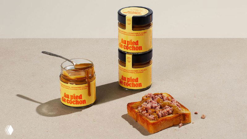 Несколько банок и тюбиков продукта разных размеров, выстроенные на столе: единая цветовая палитра и яркие оранжевые надписи на этикетках.