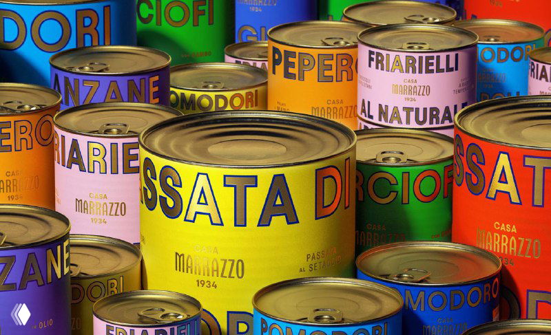 Крупный план нескольких разноцветных консервных банок Casa Marrazzo; яркие однотонные заливки, крупная золотая типографика и окантовка как элемент дизайна упаковки.