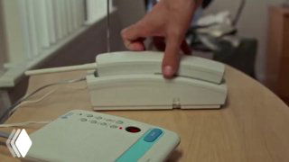 Рука поднимает стационарную телефонную трубку со стола рядом с небольшим ответчиком/магнитолой — иллюстрация идеи голосового вызова к цифровому ассистенту в контексте браузера