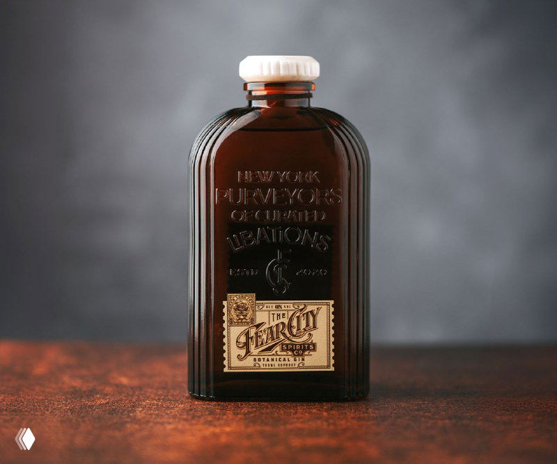Тёмная стеклянная бутылка «The Fear City» в псевдовинтажном стиле ар‑деко, небольшая золотая этикетка и крупные рельефные надписи на корпусе, нейтральный студийный фон.