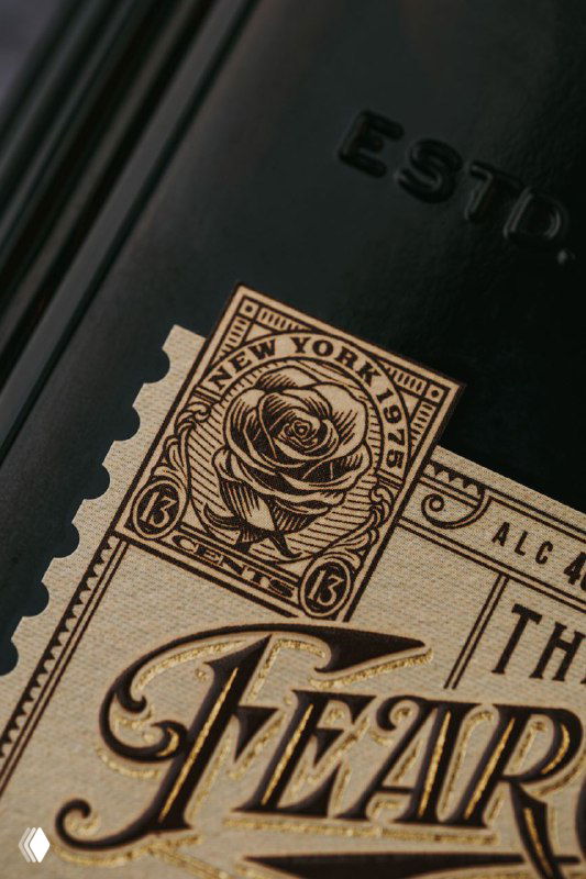 Макро‑кадр золотой этикетки «The Fear City» с орнаментом и розой, детализированная типографика, тиснение и винтажная графика в стиле ар‑деко.