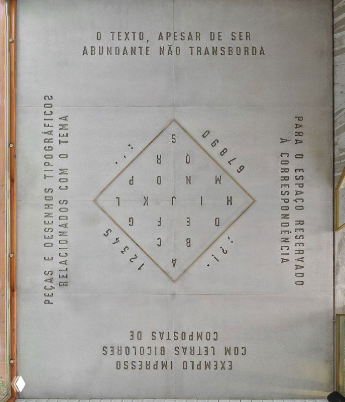 Фрагмент рельефной бетонной типографики на светло‑серой стене: ромбовидная композиция из букв и декоративных надписей в стиле отеля.