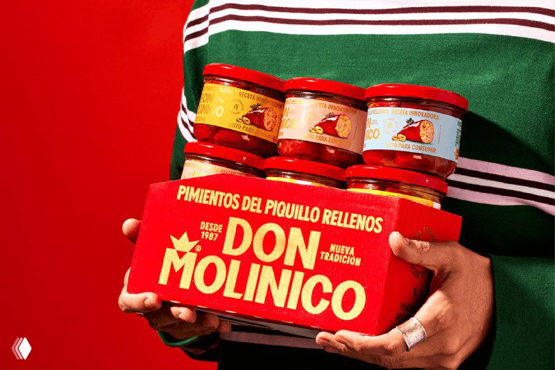 Человек держит набор банок Don Molinico в рукaх на красном фоне; видна общая композиция упаковки и логотип в ретростиле.